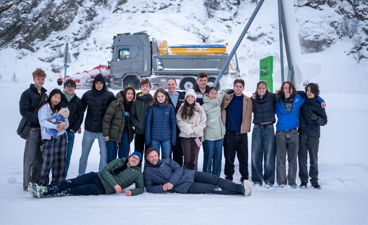 en gruppe mennesker som poserer for et bilde foran et militært kjøretøy