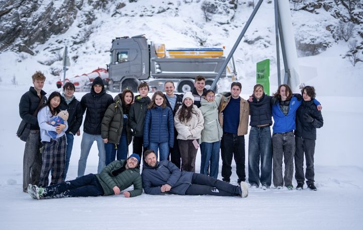en gruppe mennesker som poserer for et bilde foran et helikopter