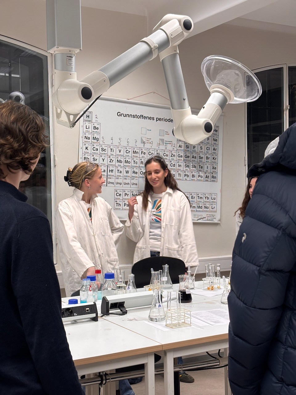 en person som står foran et bord sammen med en person i hvit frakk og hvit frakk