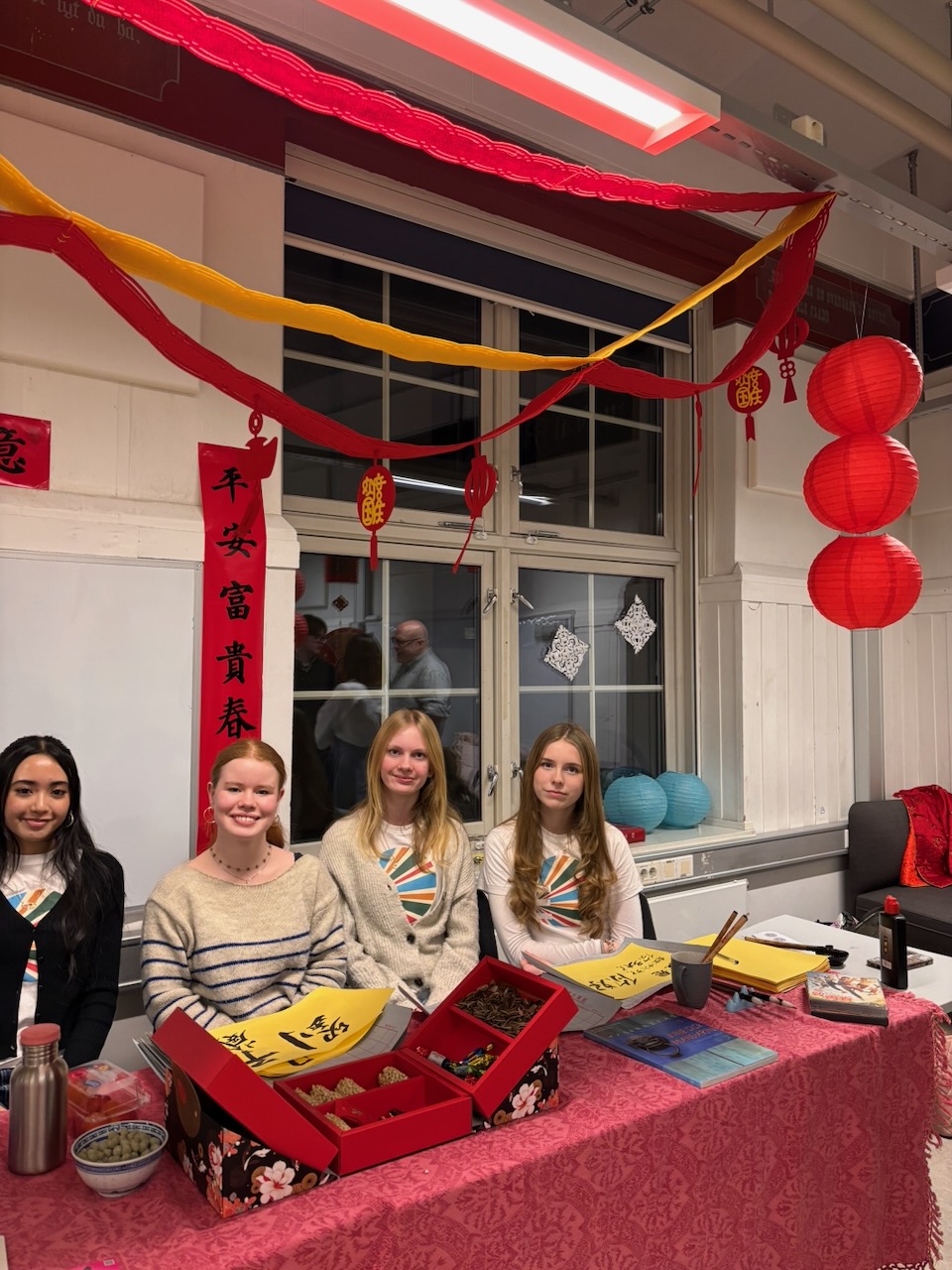 En gruppe mennesker som sitter ved et bord med en rød duk