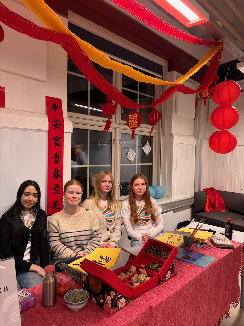 en gruppe personr som sitter ved et bord med en rød duk