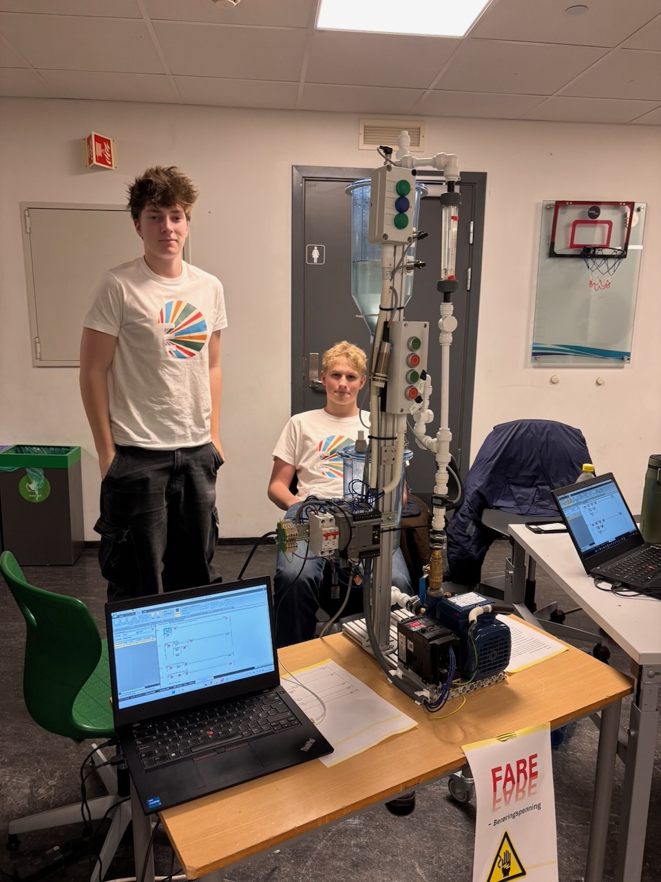 et par menn som sto i et rom med datamaskiner og et bord