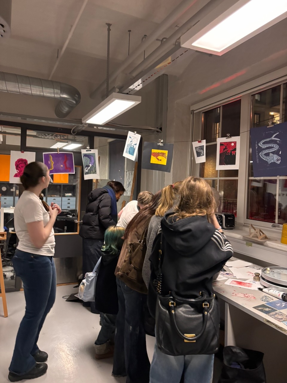 en gruppe mennesker som står i et rom med skilt og plakater på veggen