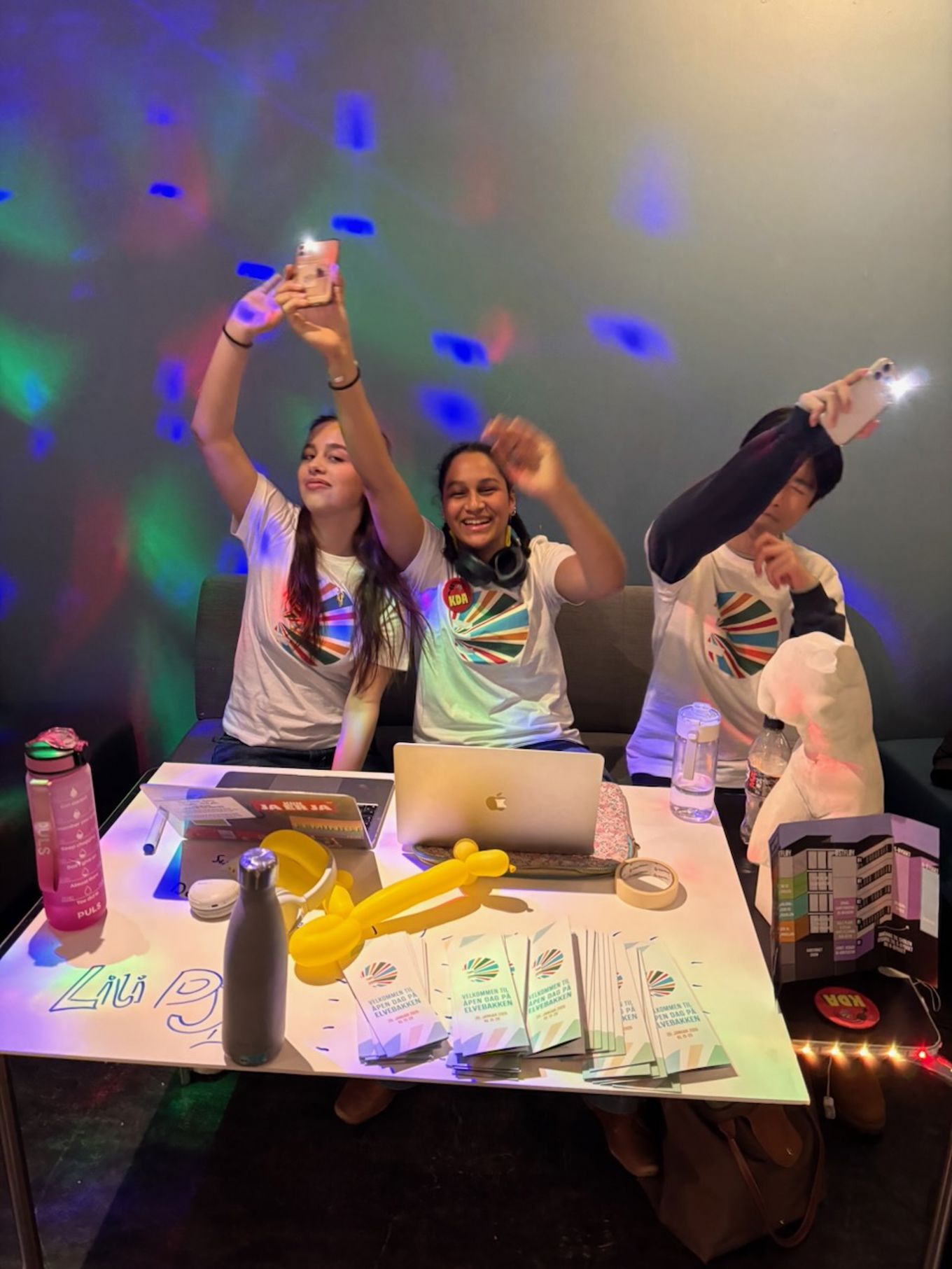 en gruppe mennesker som sitter ved et bord med en laptop og en projektorskjerm en gruppe mennesker som sitter ved et bord med en laptop og en projektorskjerm