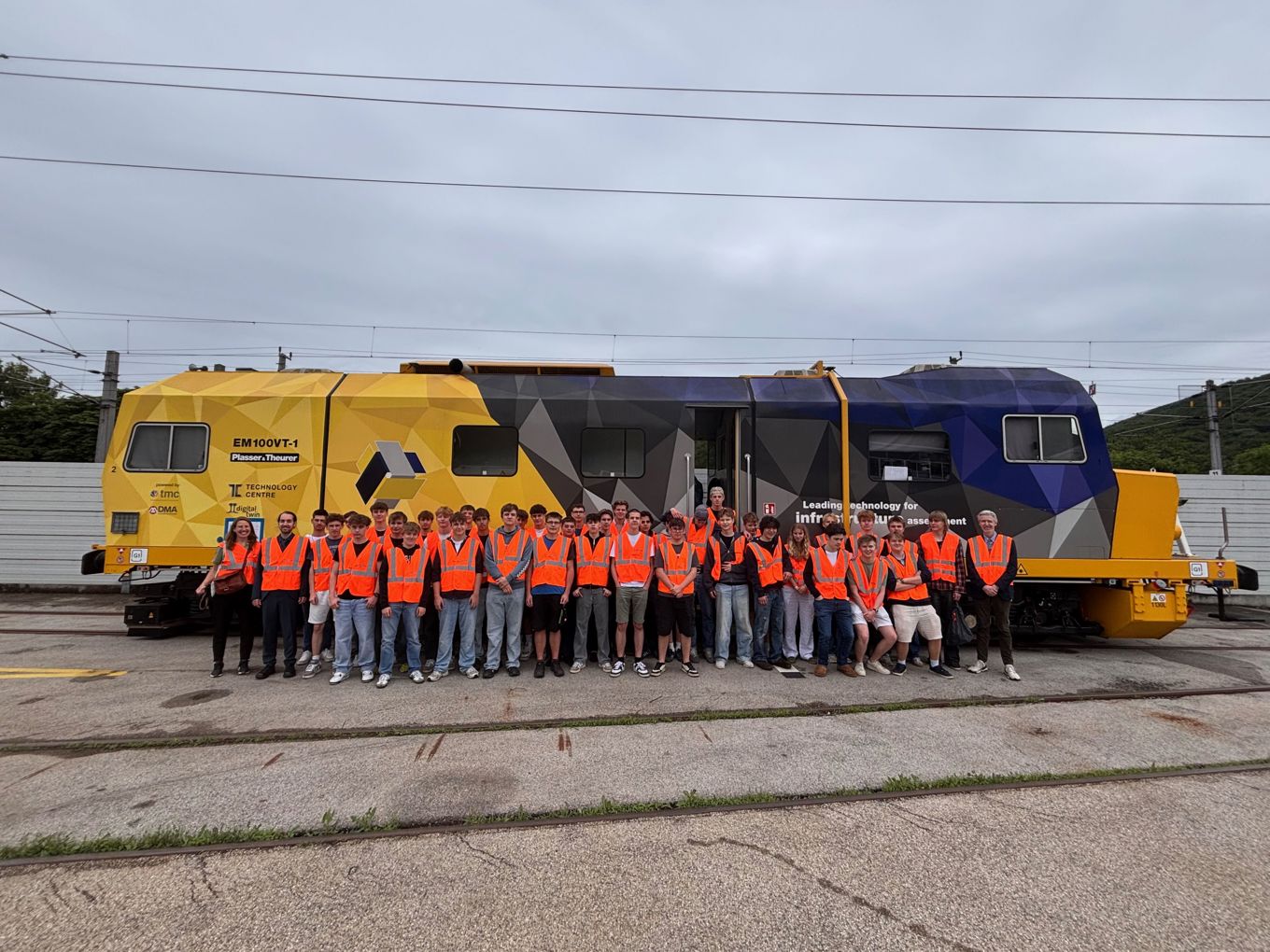 En gruppe mennesker i oransje vester står foran et tog En gruppe mennesker i oransje vester står foran et tog