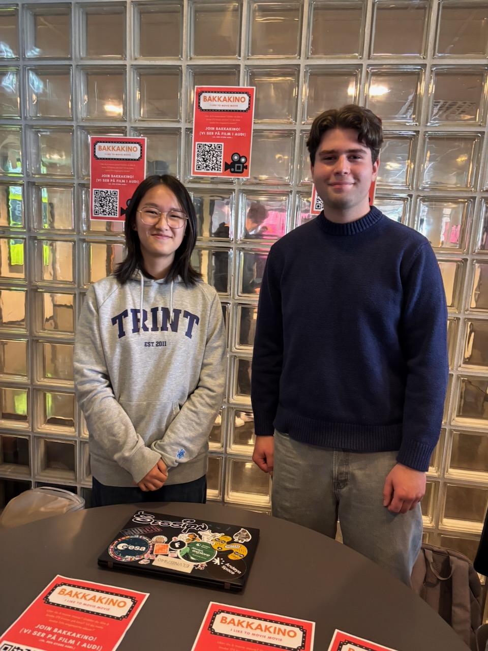 en person og en person står ved siden av et bord med bøker på