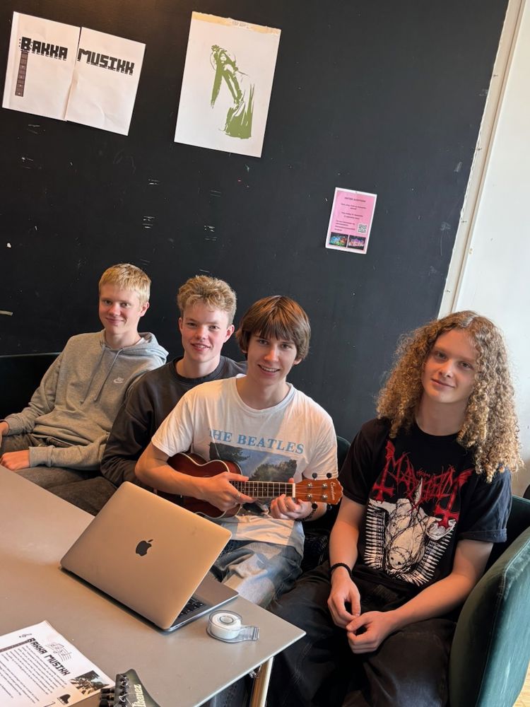 en gruppe mennesker som sitter i et rom med en bærbar PC