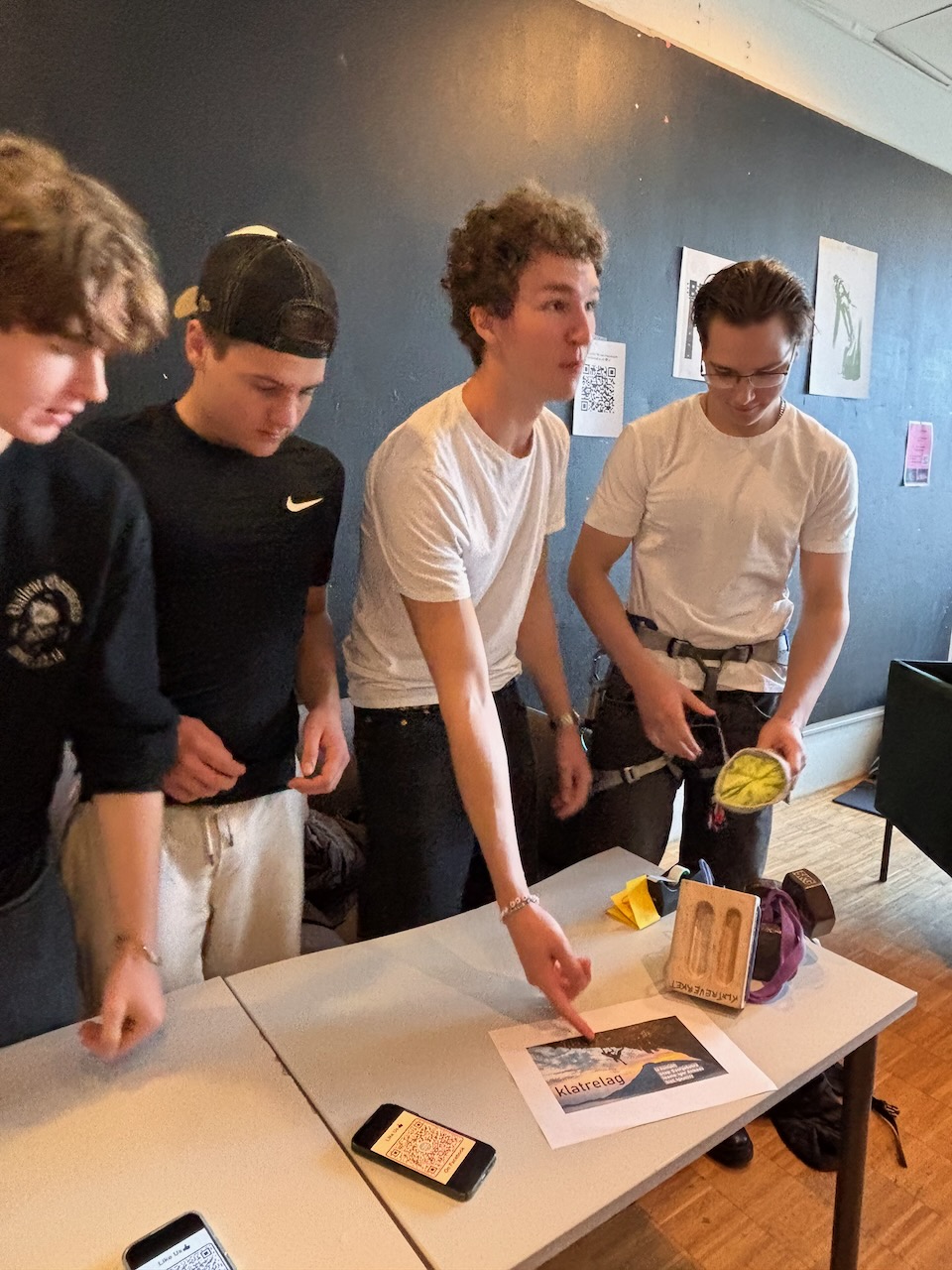 En gruppe mennesker som står rundt et bord med en bok og en telefon