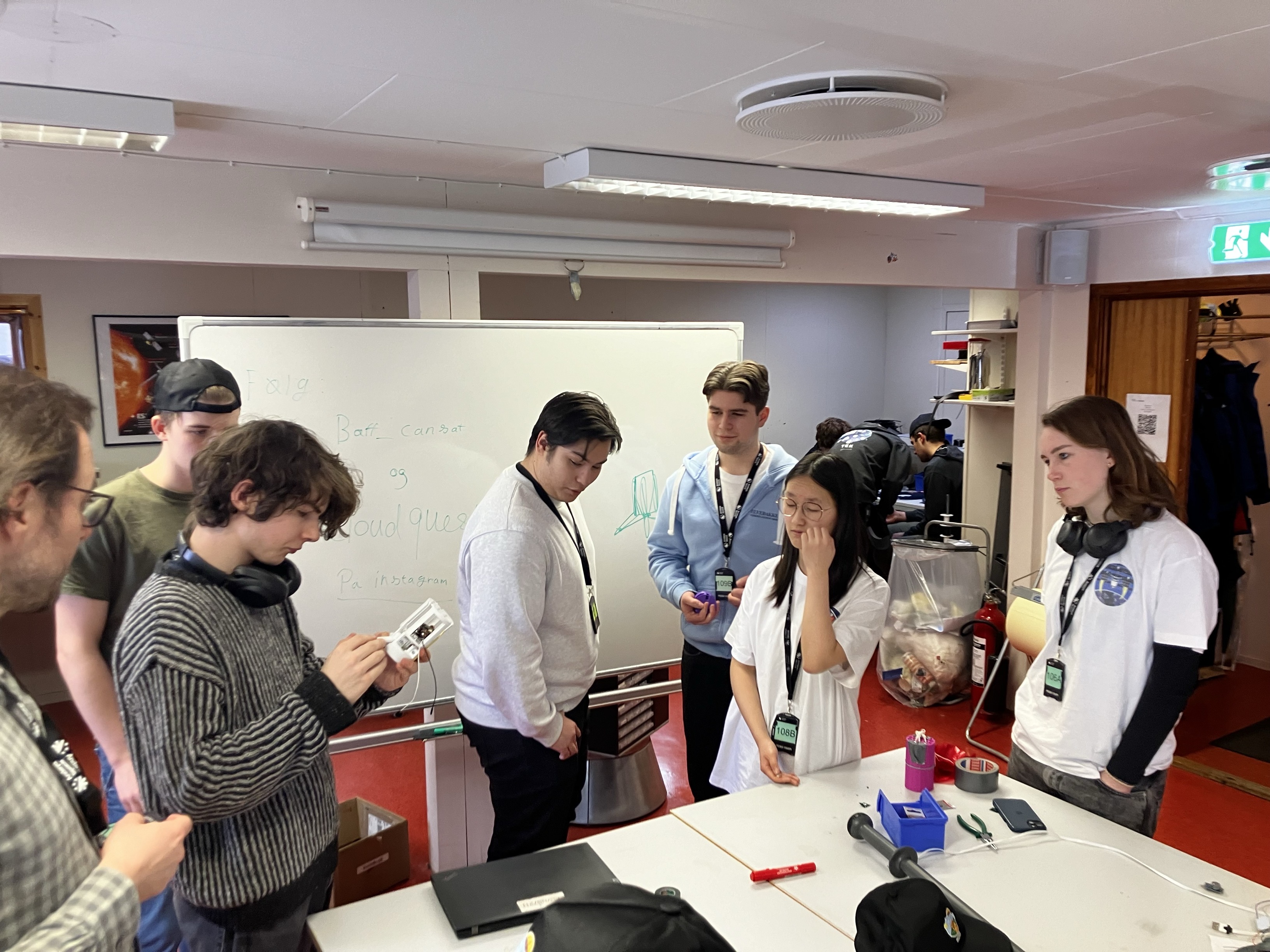 en gruppe mennesker som står rundt et bord med en tavle