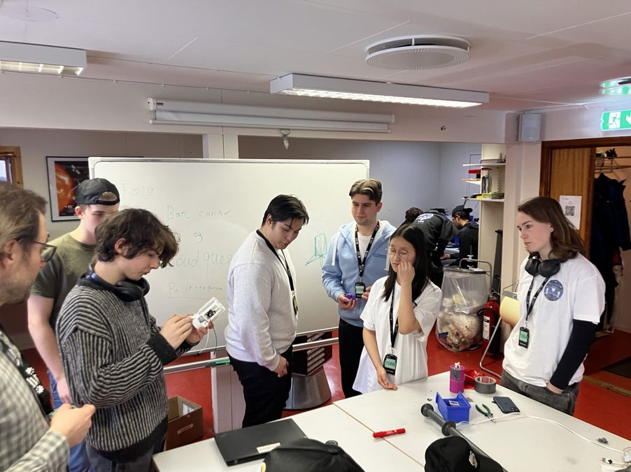 en gruppe mennesker som står rundt et bord med en tavle