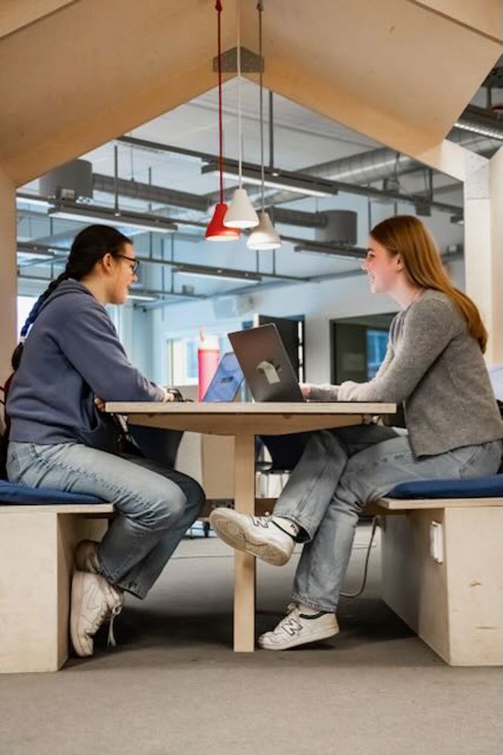 en person og en person som sitter ved et bord med bærbare datamaskiner