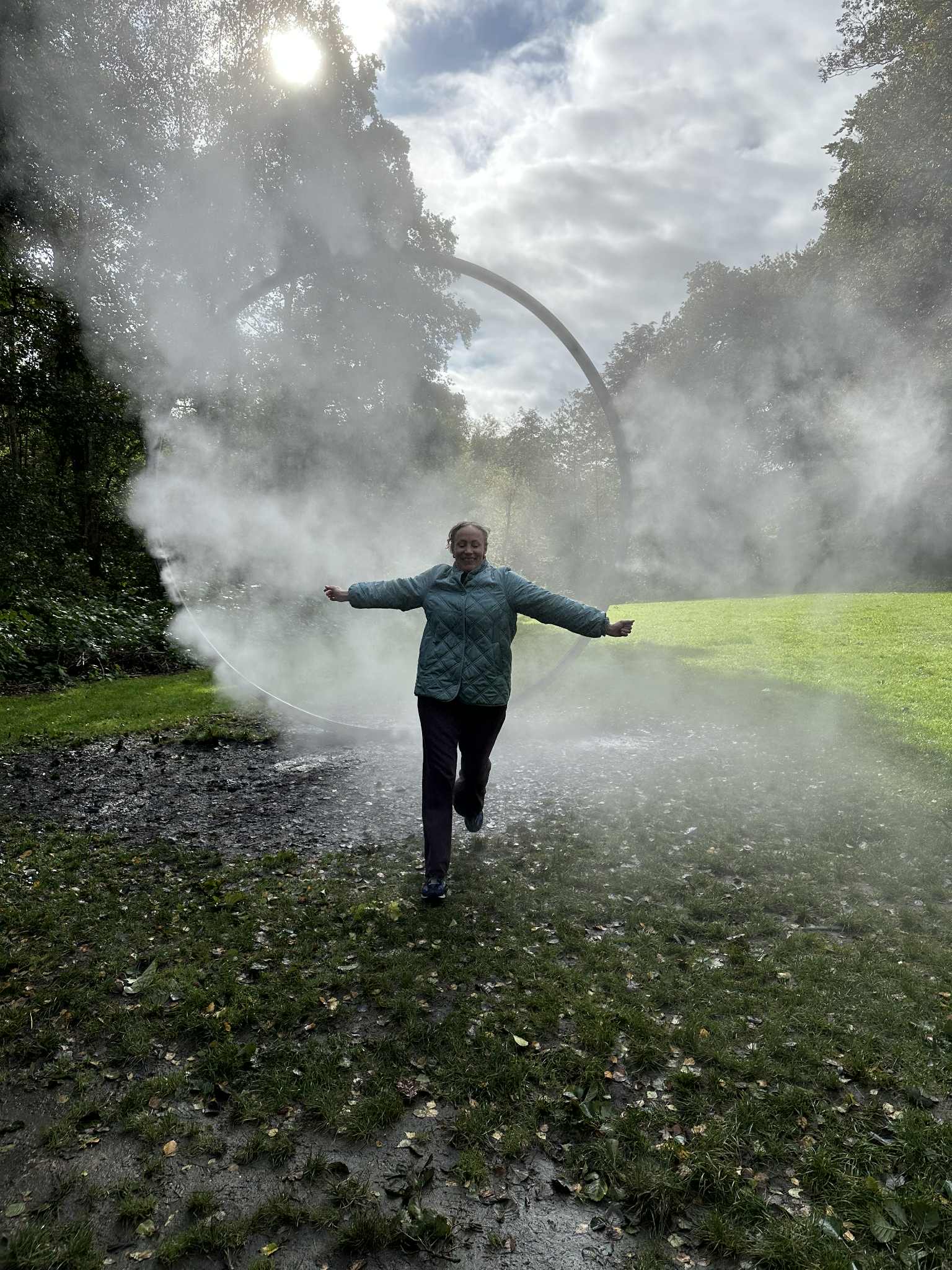 en person som står på et jorde med en stor sprinkler som sprøyter vann på dem