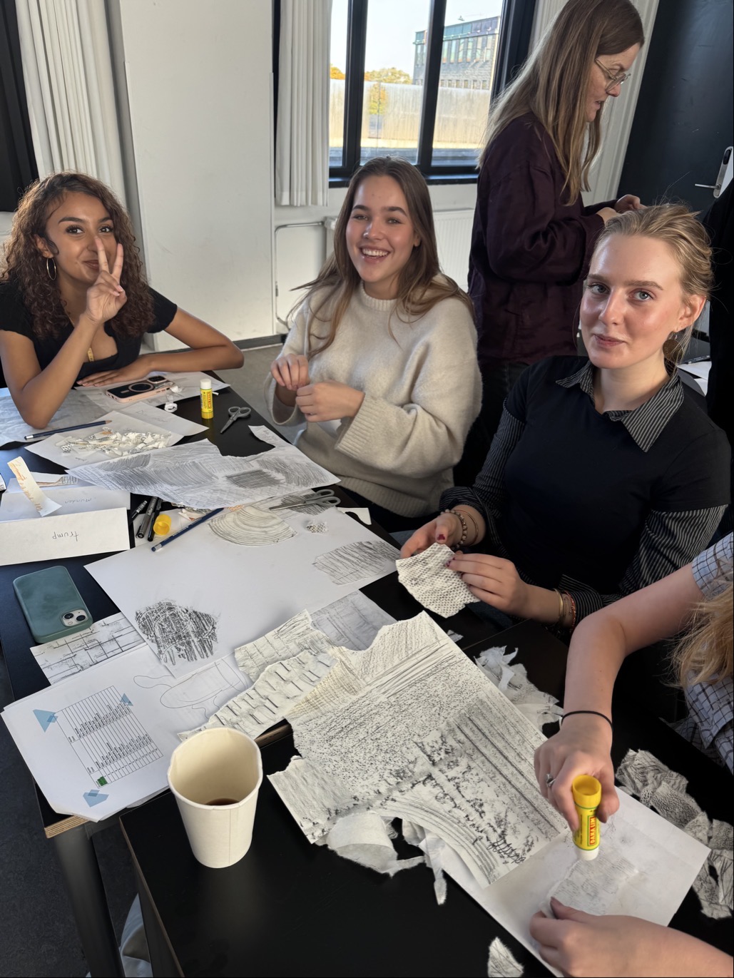 en gruppe personr som sitter ved et bord med papirer og penner