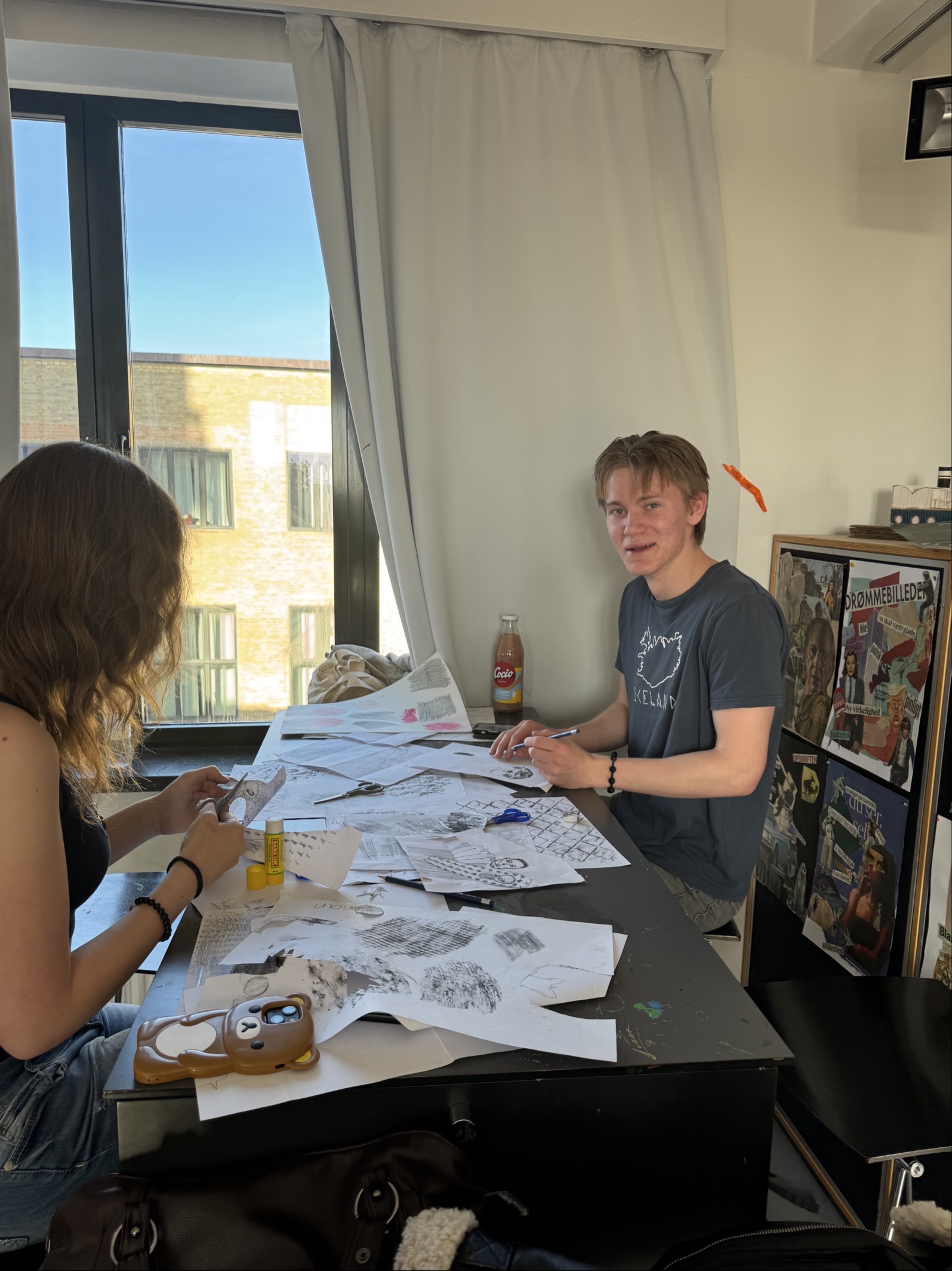 en person og en person som sitter ved et bord med et papir og en flaske brus