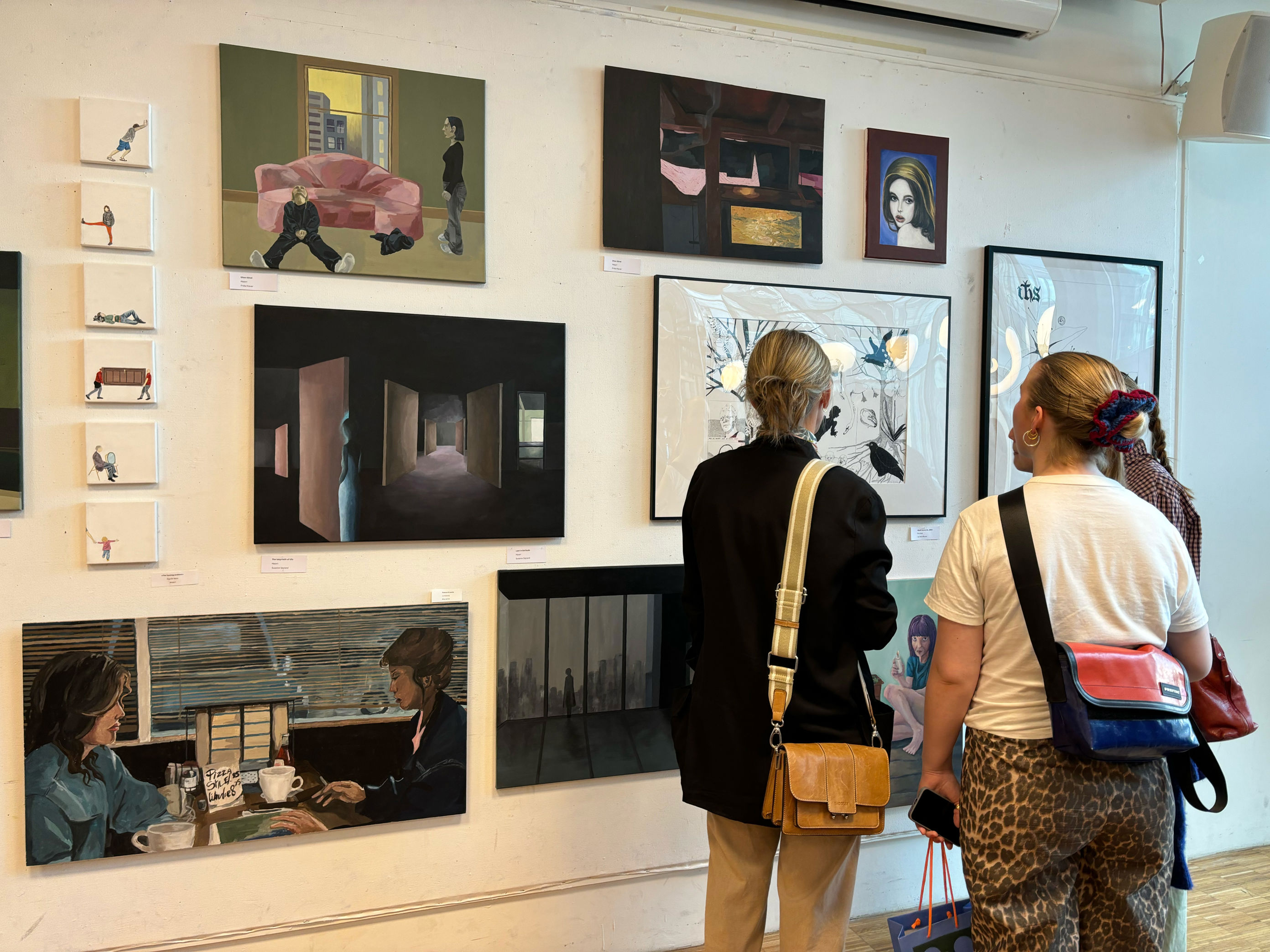 et par personr som ser på bilder på en vegg et par personr som ser på bilder på en vegg