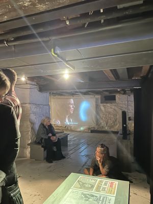 en gruppe mennesker som sitter i et rom med en projektorskjerm