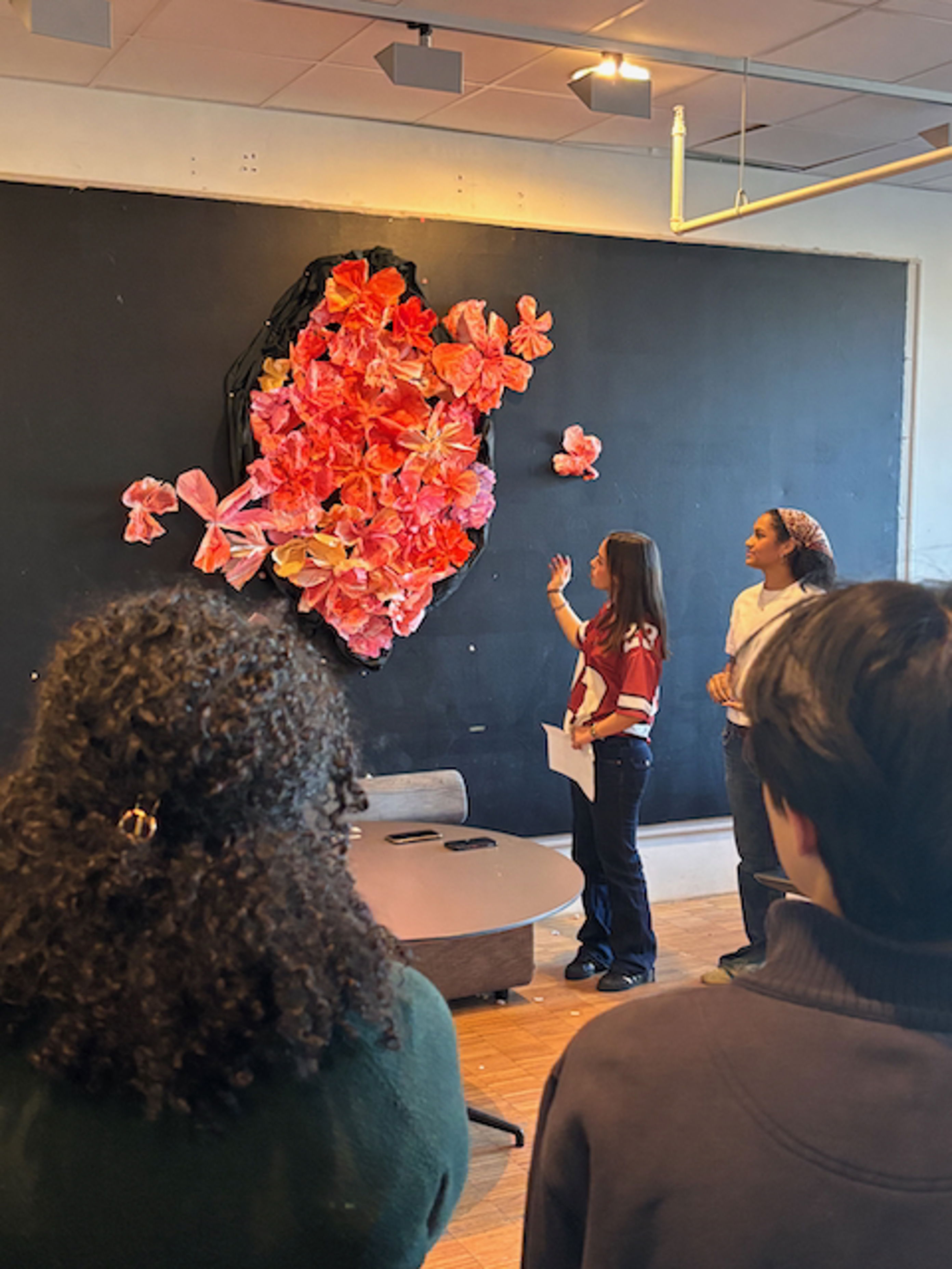 en person som står foran en blå vegg med blomster på