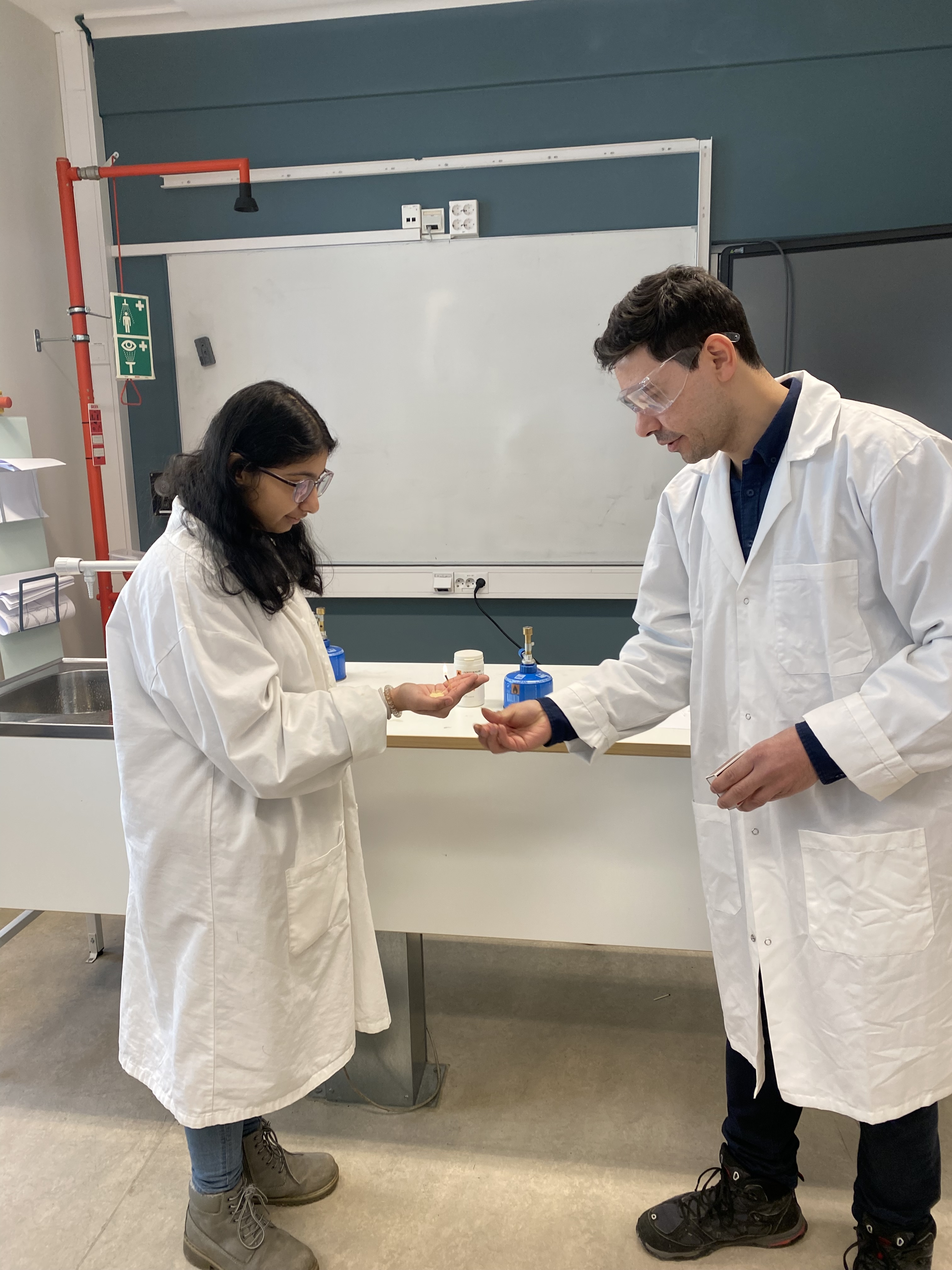 En person og en person i laboratoriefrakker som ser på et stykke papir