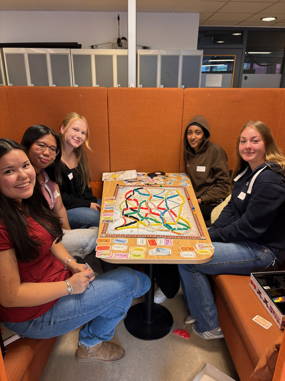 en gruppe personr som sitter ved et bord med et brettspill