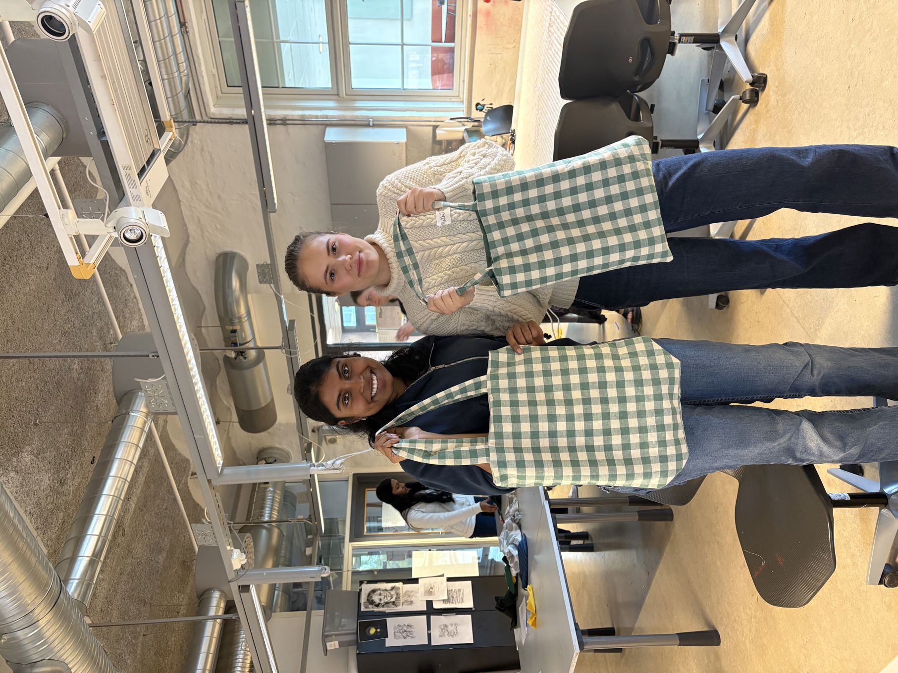 en gruppe mennesker som står i et rom med bord og stoler