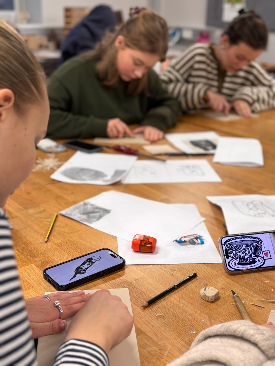 En gruppe mennesker som sitter ved et bord og ser på en telefon