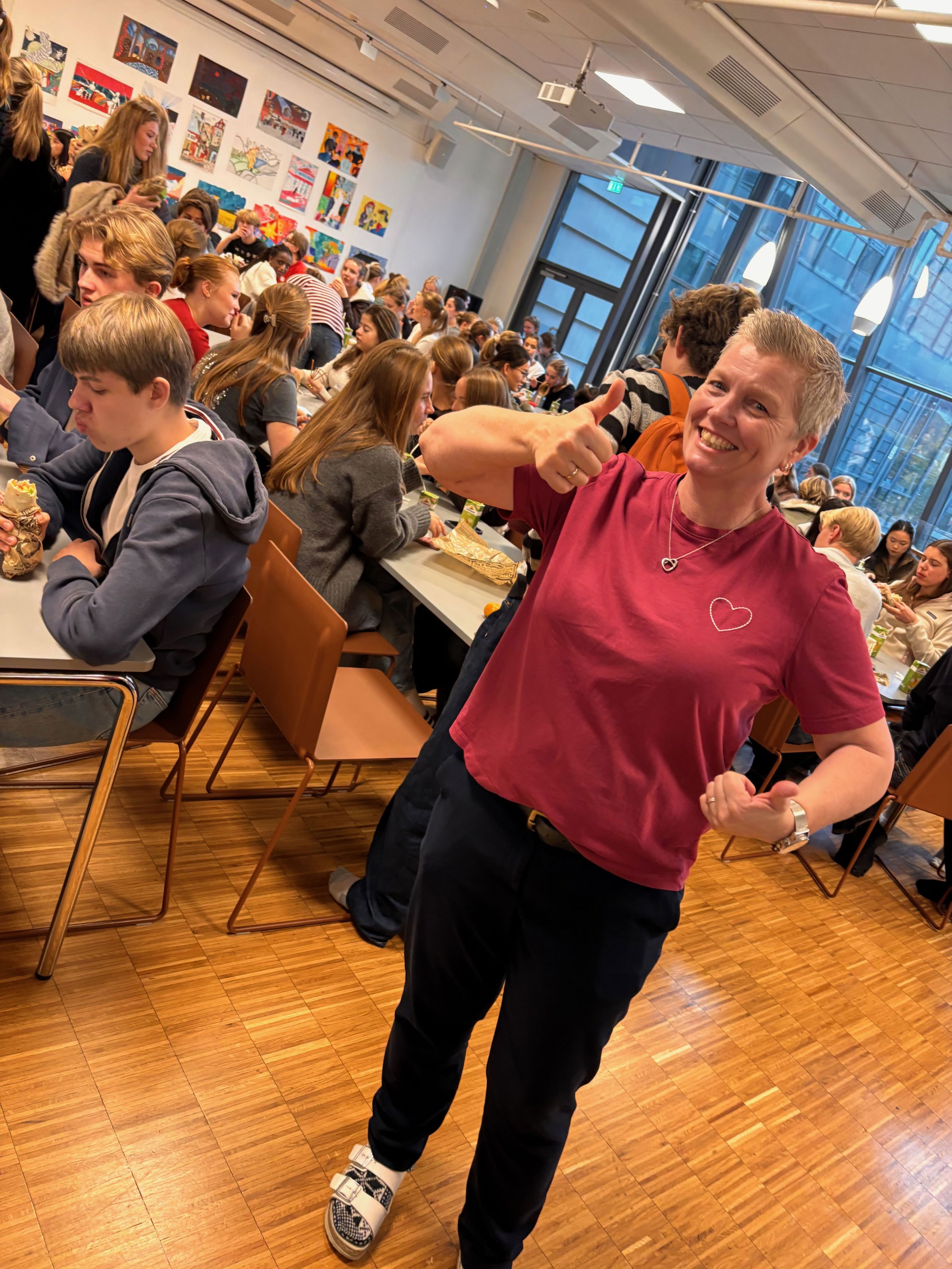 en person som holder armen opp i et klasserom sammen med andre mennesker