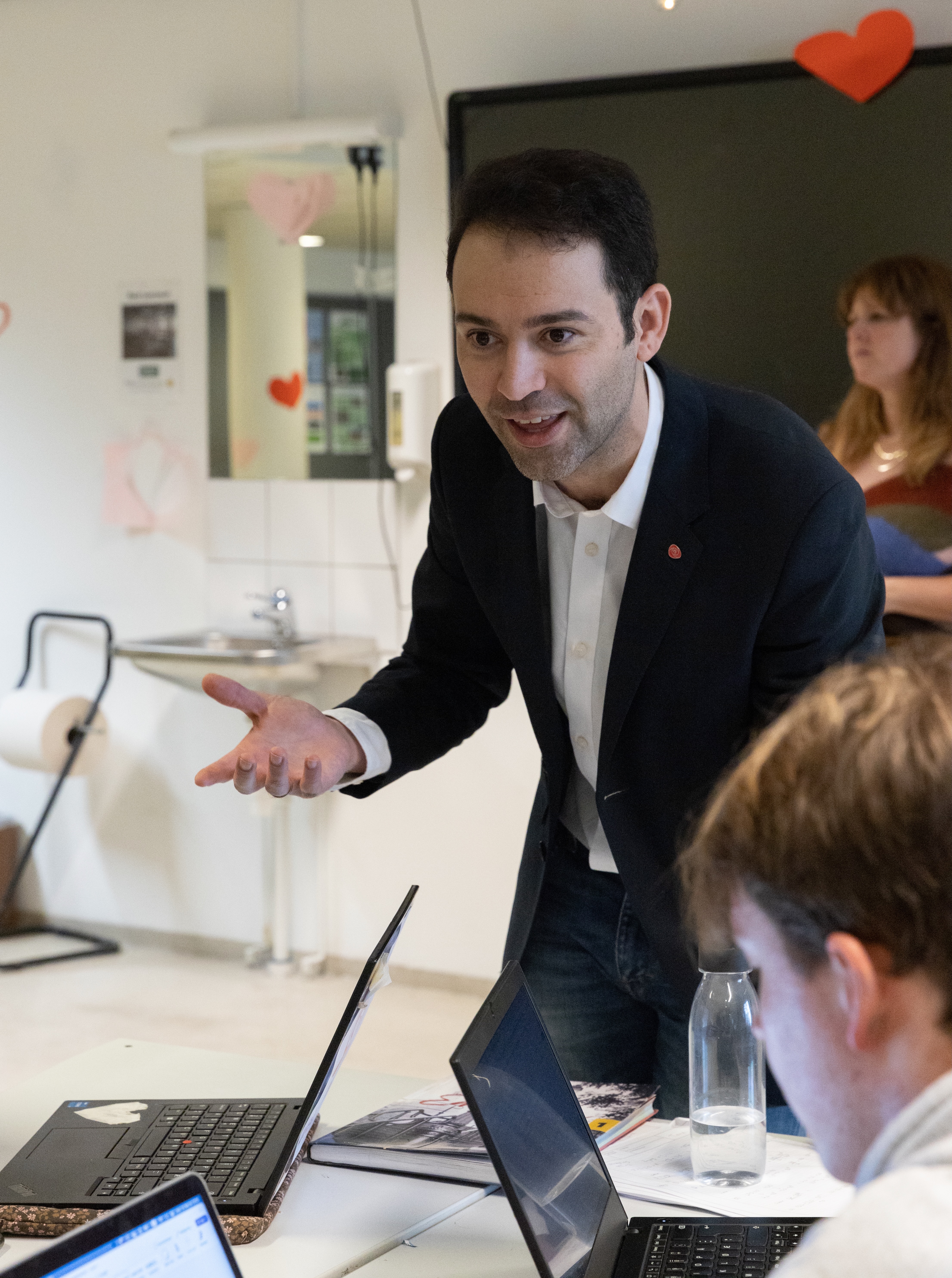 en person i dress som står foran en bærbar datamaskin