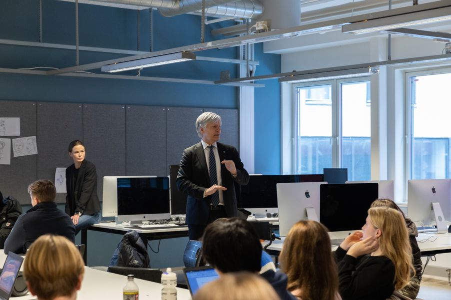 en person som står foran en gruppe mennesker i et rom