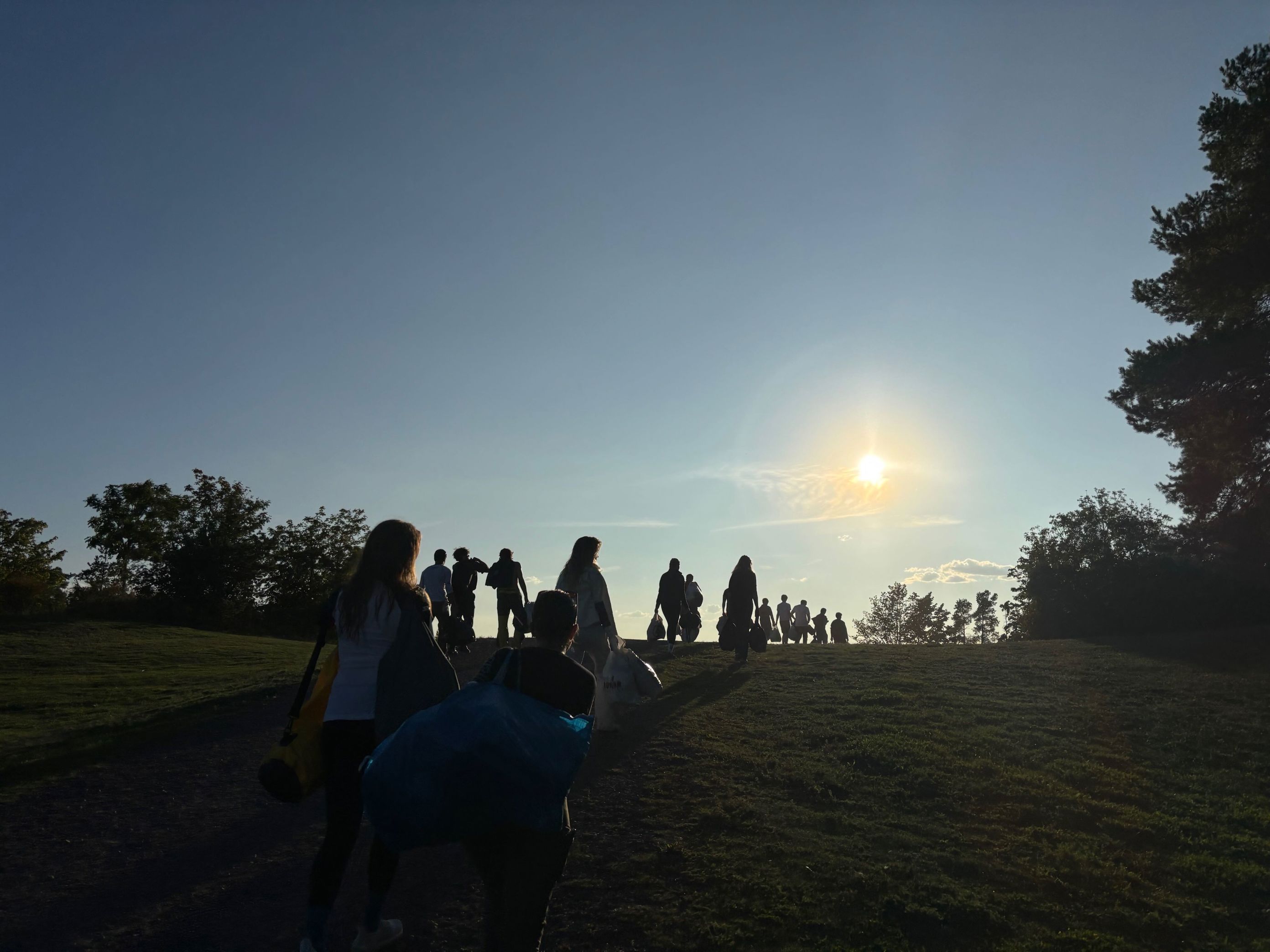 en gruppe mennesker som går på en sti med solen i bakgrunnen